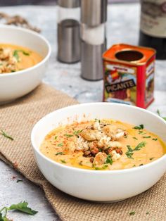 two white bowls filled with soup sitting on top of a table next to a can