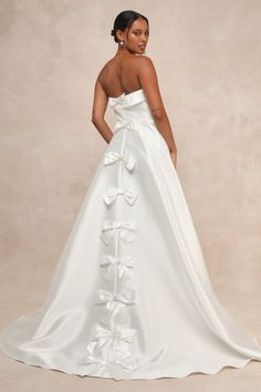 a woman in a white wedding dress with flowers on the skirt and her back to the camera