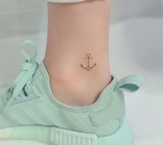 a small anchor tattoo on the foot of a woman's ankle is seen in this image