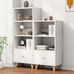 a white bookcase with three drawers next to a potted plant on the floor