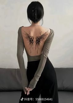 the back of a woman's body with black wings on her upper and shoulder