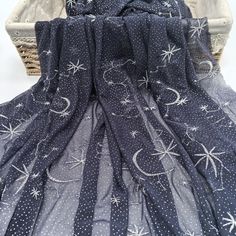 a black and white dress with stars and moon designs on it, sitting in front of a basket