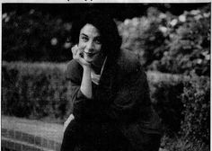 an old black and white photo of a woman leaning against a wall with her hand on her face