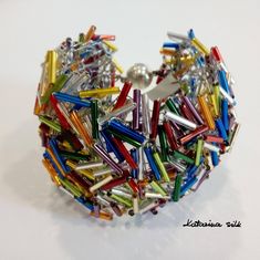 there is a bracelet made out of many different colored pins and silver metal beads on it