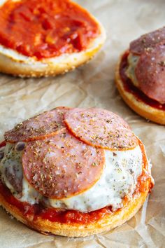 three mini pizzas with cheese and pepperoni on them are sitting on wax paper