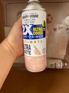 a hand is holding up a can of ultra matte paint in front of a cabinet