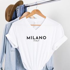 Milano Italy V-neck Soft Cotton T-shirt. Made With Love & Purpose. This T-shirt is a Love at first sight. There's nothing better than a T-shirt that makes you feel comfortable and stylish at the same time. Style this modern Paris Tee with a skirt, jeans or leggings, add a piece of jewelry, put on your favorite shoes and you're ready to go make memories. This tee makes a perfect gift for all Fashion Lovers.  GENERAL INFORMATION - Bella And Canvas Brand Shirts - Rolled Sleeves in pictures is for s Cotton V-neck Top With Letter Print, Trendy V-neck T-shirt With Graphic Print, White V-neck T-shirt With Letter Print, V-neck T-shirt With Letter Print In Relaxed Fit, Trendy V-neck Shirt With Graphic Print, White V-neck Top With Text Print, V-neck Cotton T-shirt With Logo Print, Cotton V-neck T-shirt With Logo Print, Cotton V-neck T-shirt With Text Print