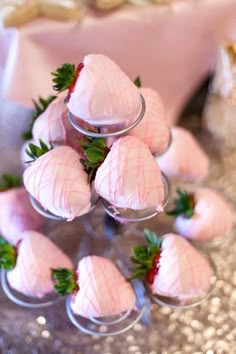 strawberries are arranged in small glass cups on a silver tablecloth with pink and gold sequins