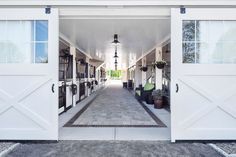 an open white garage door leading to another room with potted plants on either side