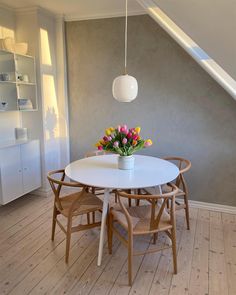 a white table and chairs with flowers in a vase on the top of one of them