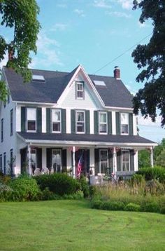 a large white house sitting in the middle of a lush green field on a sunny day