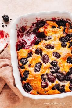 a casserole dish with berries in it on a table next to a spoon