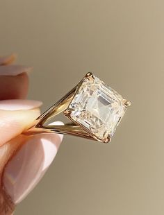 a hand holding a yellow diamond ring in it's right hand, with the center stone missing