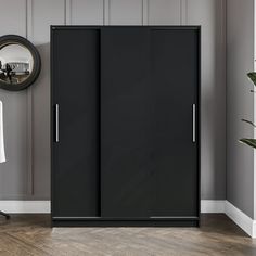 a room with a chair, mirror and two black closets on the wall in it