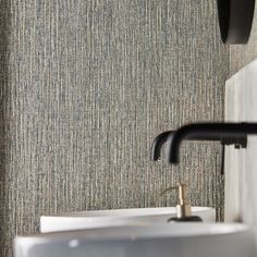 a bathroom sink sitting under a faucet next to a wall mounted soap dispenser