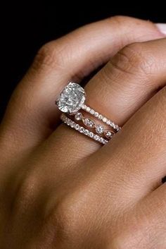 a woman's hand with two wedding rings on her left and an engagement ring on her right