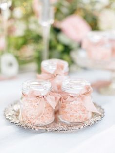 small jars filled with pink sugar sit on a silver platter