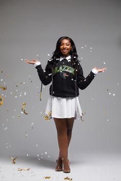 a woman is standing in front of confetti falling from her hands and arms