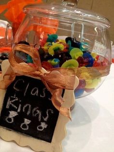 a glass jar filled with gummy bears sitting on top of a table next to a sign