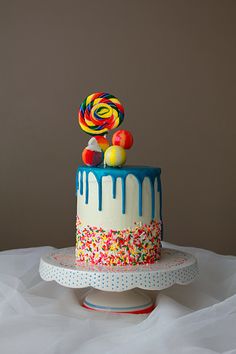 a birthday cake decorated with sprinkles and lollipops on top