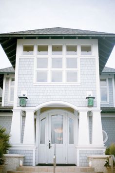 a white house with two large windows and steps leading up to the front door area