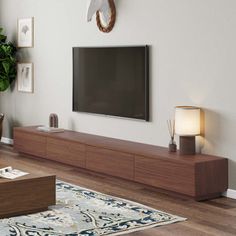 a flat screen tv mounted on the wall above a wooden entertainment center in a living room