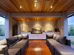 an outdoor living area with couches, cabinets and lights on the ceiling is lit by recessed lighting