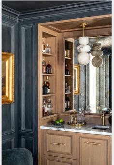 an elegant bathroom with marble counter tops and wooden cabinets, along with hanging lights above the sink