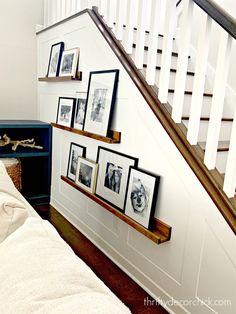 there are pictures on the wall next to the stairs and under the bannister