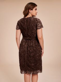 a woman wearing a brown lace dress with short sleeves and an open back, standing in front of a beige background