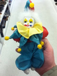 a hand holding a clown doll in a store