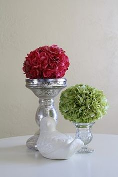 two vases with flowers in them sitting on a white table next to each other