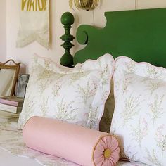 a green headboard with two pillows and a pink pillow on the bottom one side