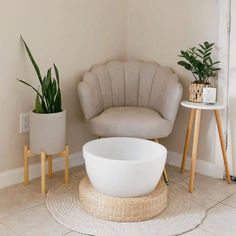 a white bowl sitting on top of a rug next to a chair and potted plant