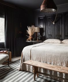 a large bed sitting next to a window in a dark colored room with striped carpet