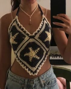 a woman is taking a selfie with her cell phone and wearing a crocheted crop top