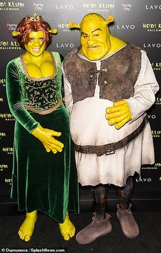 two people in costumes standing next to each other on a black carpeted area with a wall behind them