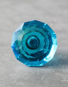 a blue glass object sitting on top of a cement floor next to a white wall