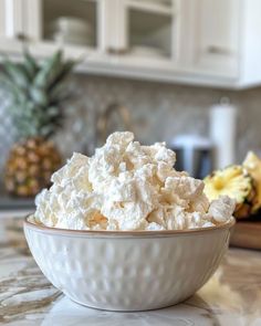 a white bowl filled with cottage cheese on top of a counter next to pineapples