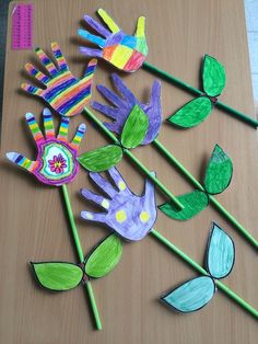 handprinted flowers and leaves on a table with colored pencils next to them