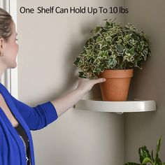 a woman is pointing at a potted plant on a shelf