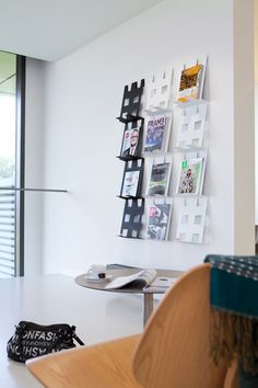 a white table topped with a laptop computer next to a wall mounted book shelf filled with books