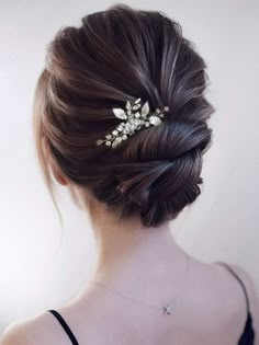 a woman wearing a hair comb with leaves on it's back and her hair in a low bun