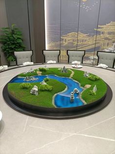 a round table with green grass and blue water in the center, surrounded by chairs