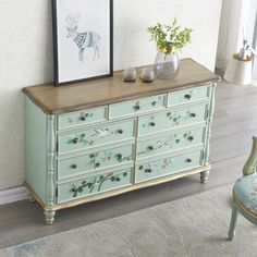 an old dresser with flowers and pictures on the top is painted in light blue, while a chair sits next to it