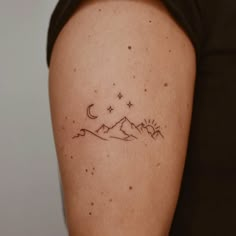 a woman with a tattoo on her arm that has mountains and stars in the sky