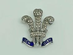 A gorgeous vintage art deco rhodium finished sterling silver brooch in rare prince of wales feathers design. Decorated with blue enamel ICH DIEN banner and set with round cut paste which are meant to simulate diamonds. A rare piece by quality maker Ciro. Maker/Markings: Marked SCP for Silver Ciro Pearls Condition: Very Good Used Condition - Please look at photos Measurements: 1 1/8" x 7/8" wide ~ 28 x 23mm Weight: 6.4g Formal Silver Enamel Brooches, Formal Silver Enamel Brooch Pin, Silver Victorian Enamel Brooches, Victorian Silver Enamel Brooches, Vintage Silver Enamel Pins, Ornate Silver Enamel Brooches, Vintage Silver Enamel Pin Collectible, Vintage Silver Collectible Enamel Pin, Sterling Silver Brooch