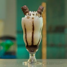 a milkshake with chocolate and whipped cream in a glass on a counter top