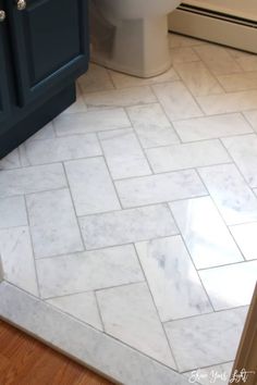 a white toilet sitting in a bathroom next to a blue cabinet and counter top on a wooden floor