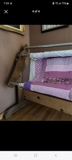 a wooden bed frame with purple and white quilt on it